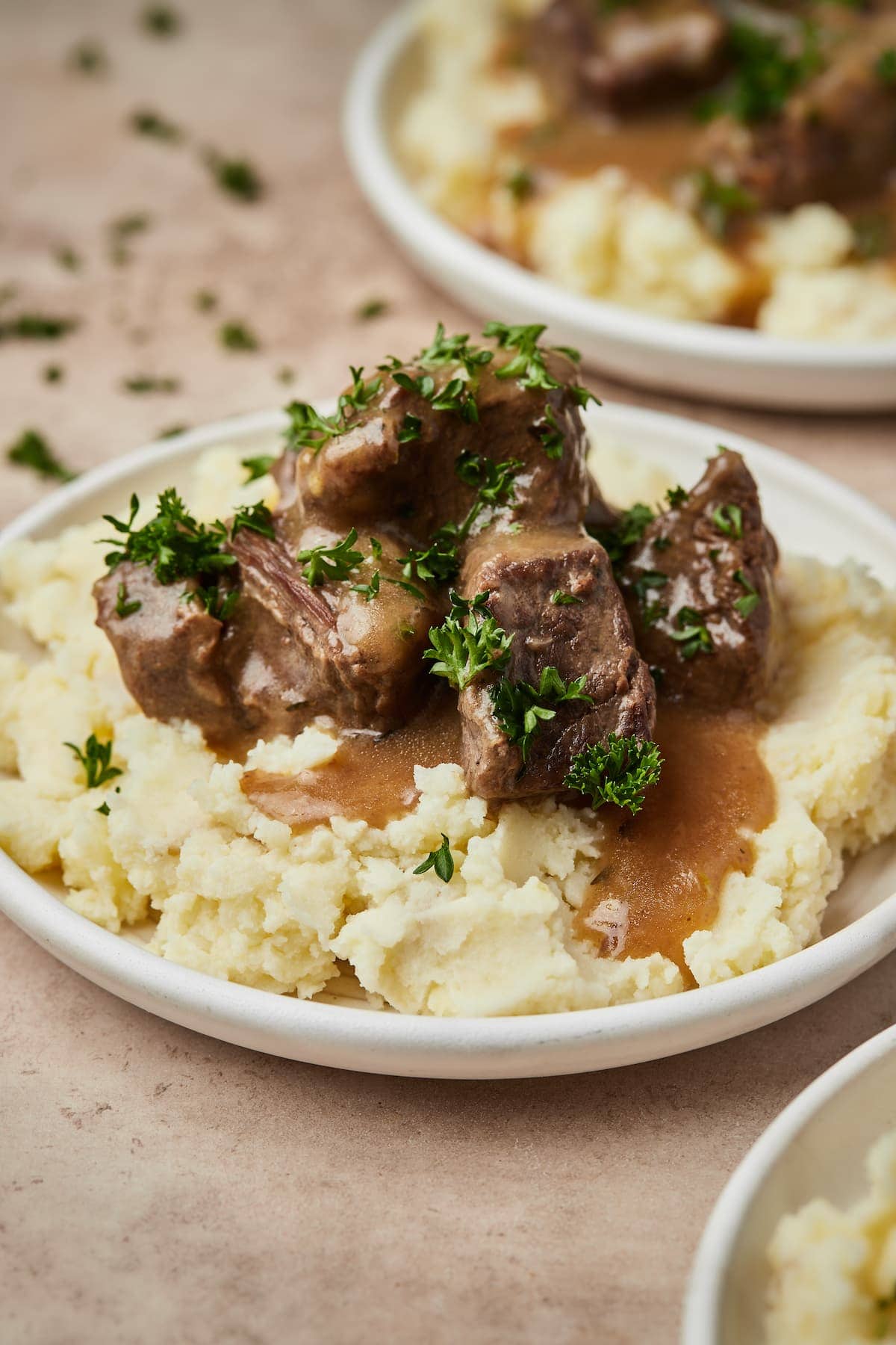 Instant Pot cubed beef and gravy served over a bed of mashed potatoes on a plate.