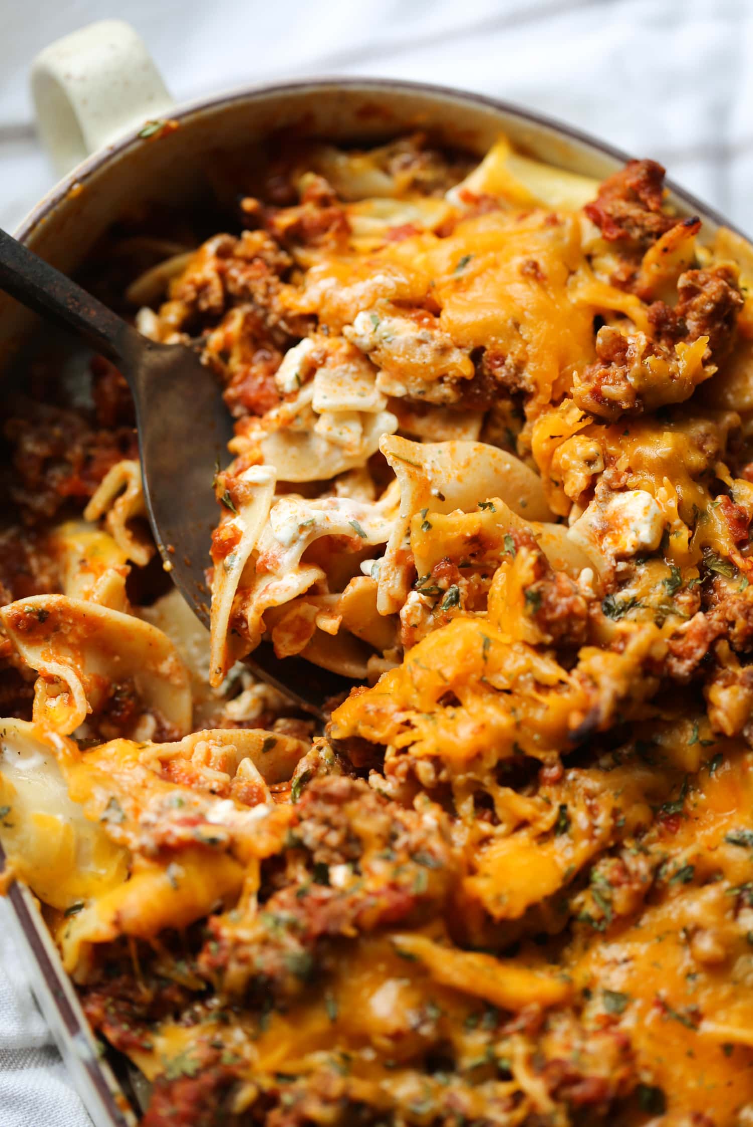 Sour cream noodle bake in a casserole dish with a spoon.