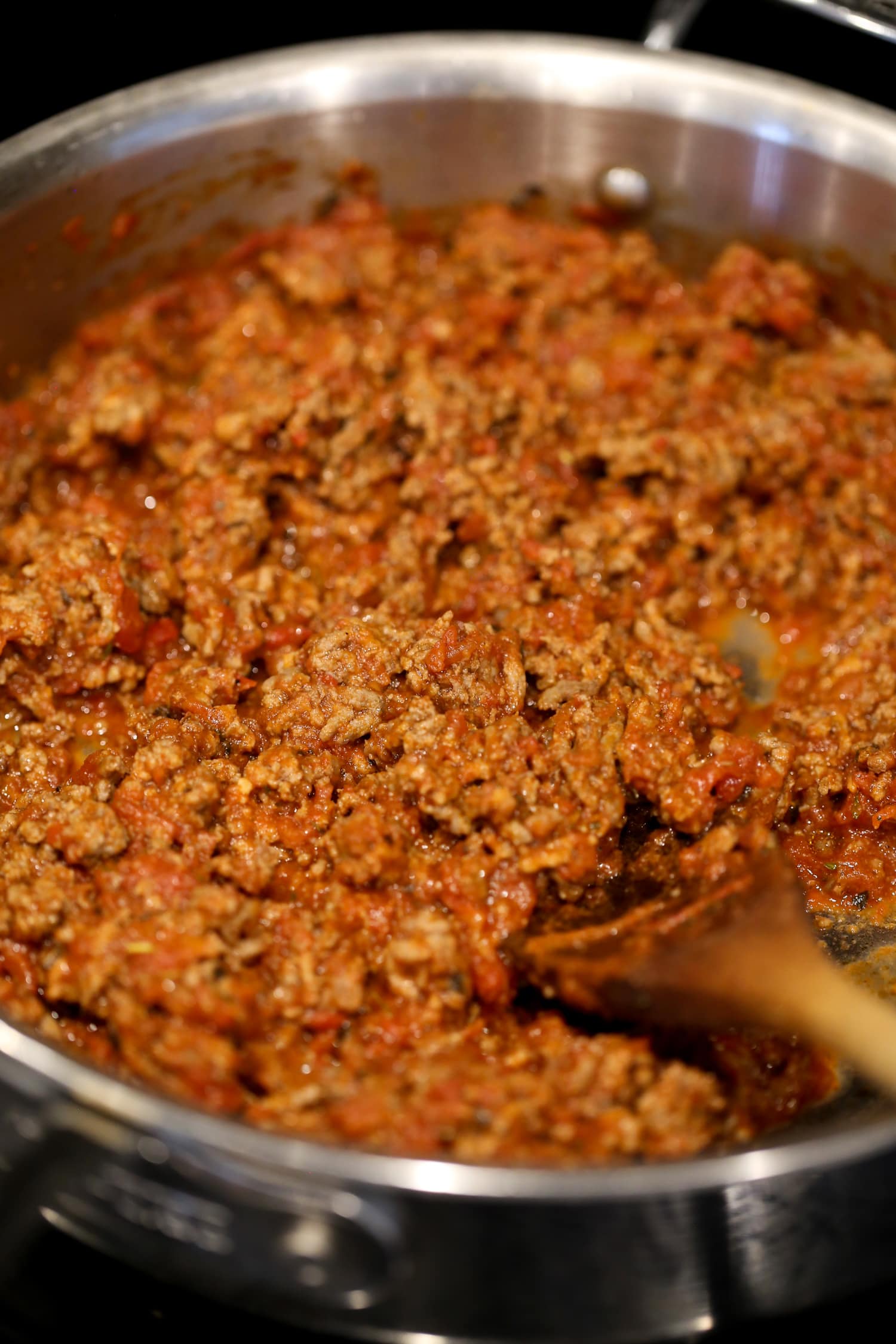 Meat sauce in a pot with a wooden spoon.