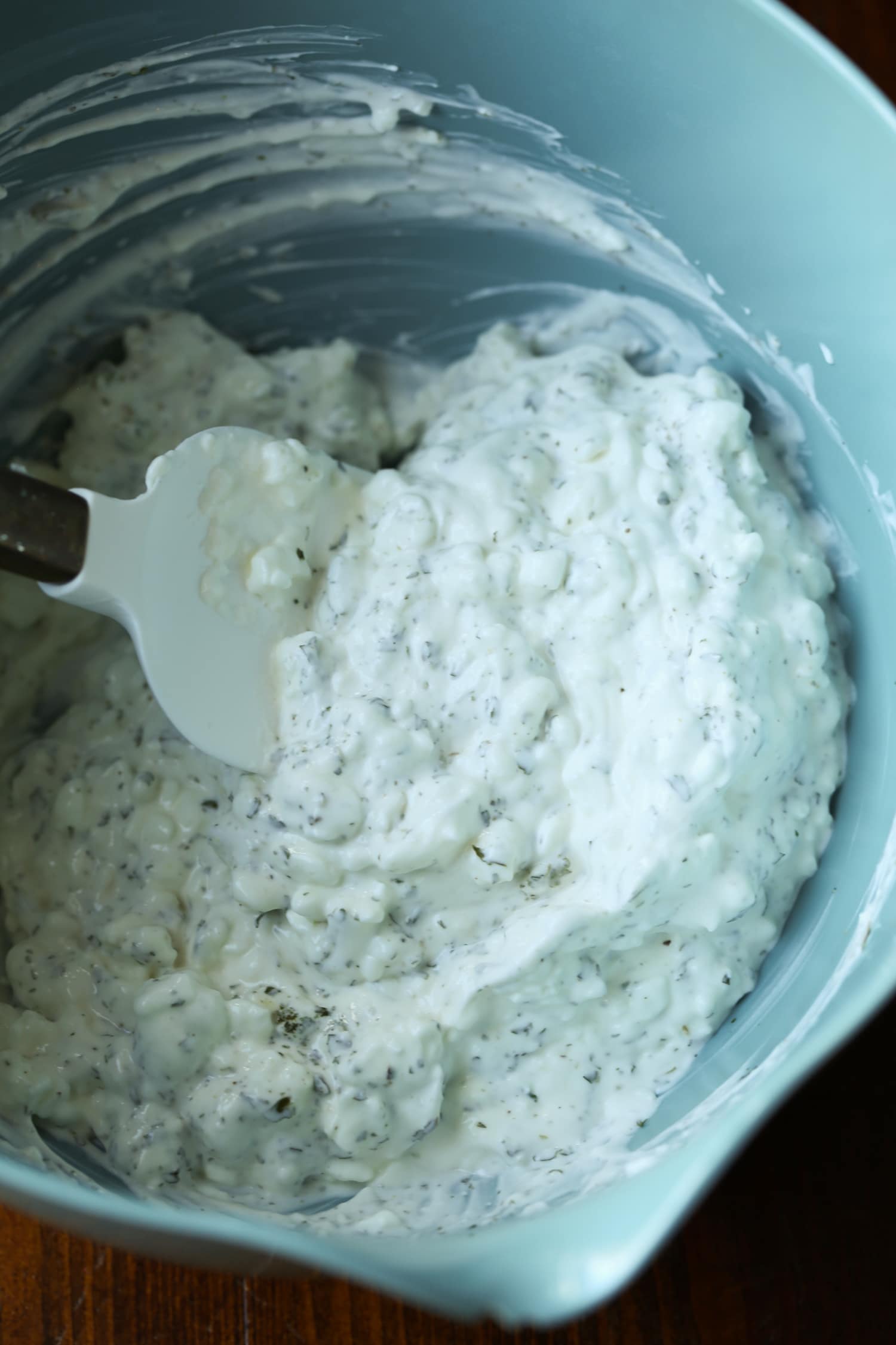 Sour cream is stirred together with cottage cheese and herbs.