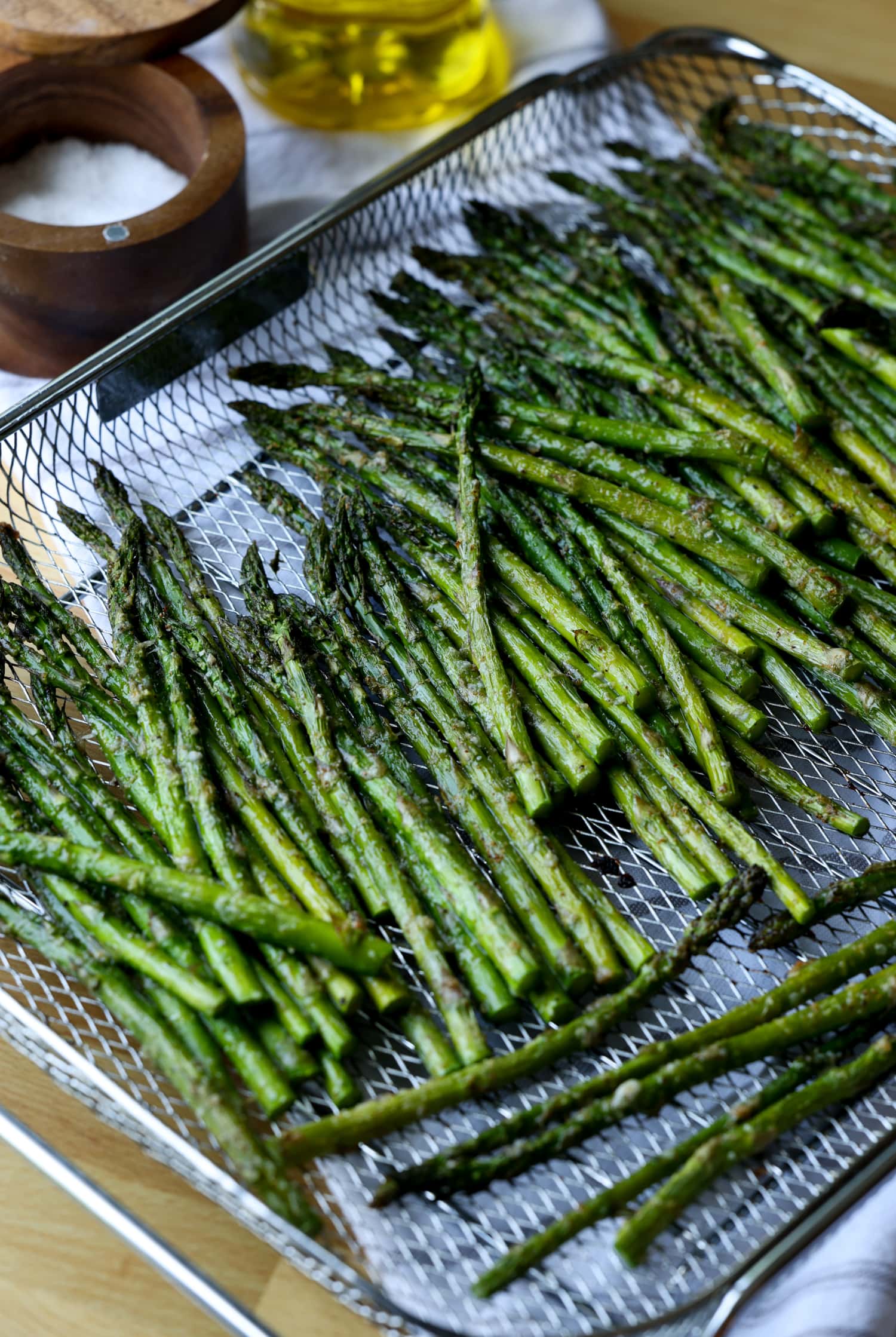 Air fryer asparagus spears spread out over a mesh cooling rack.