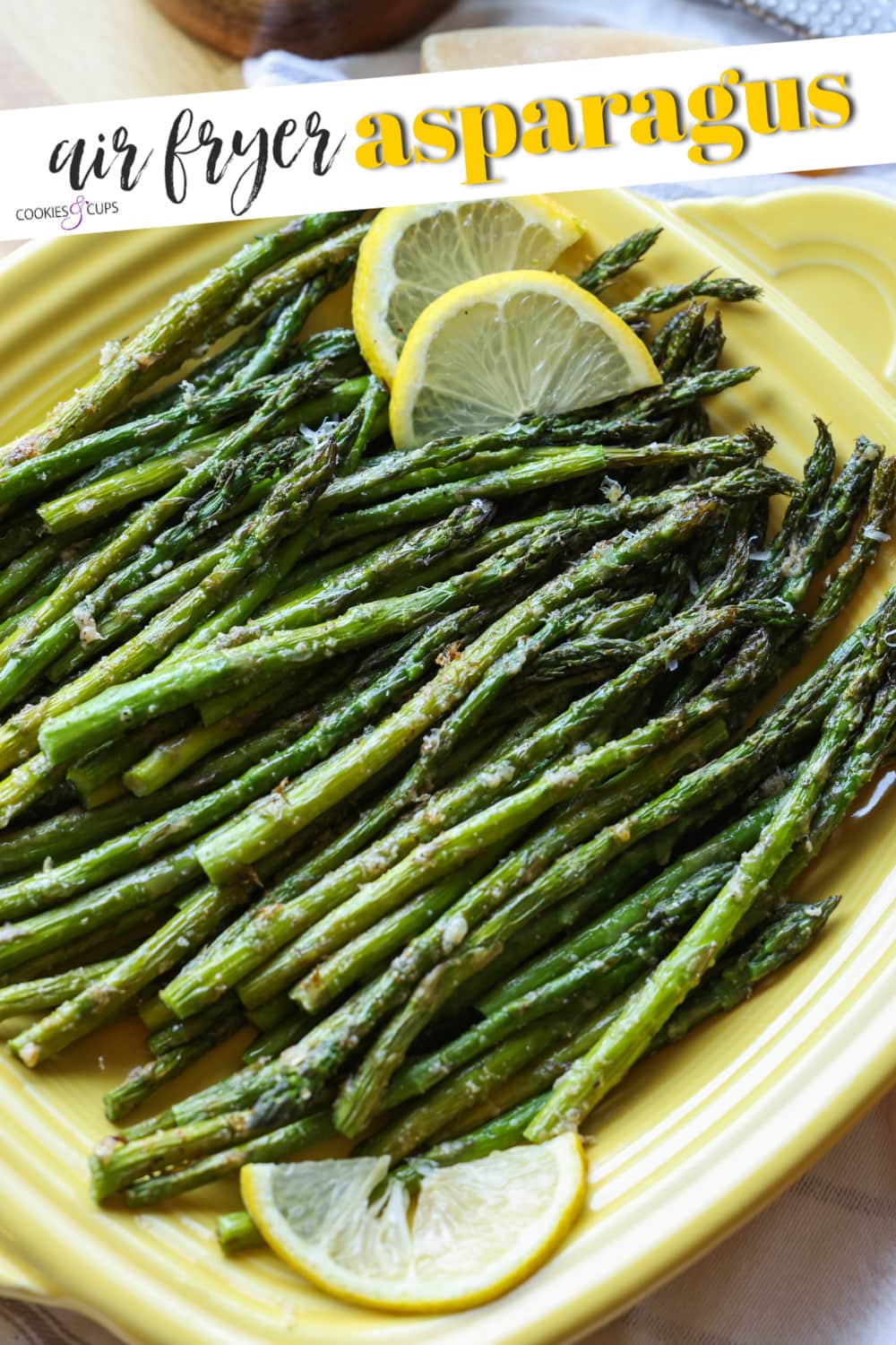 Roasted air fryer asparagus on a yellow square serving platter, garnished with lemon slices.