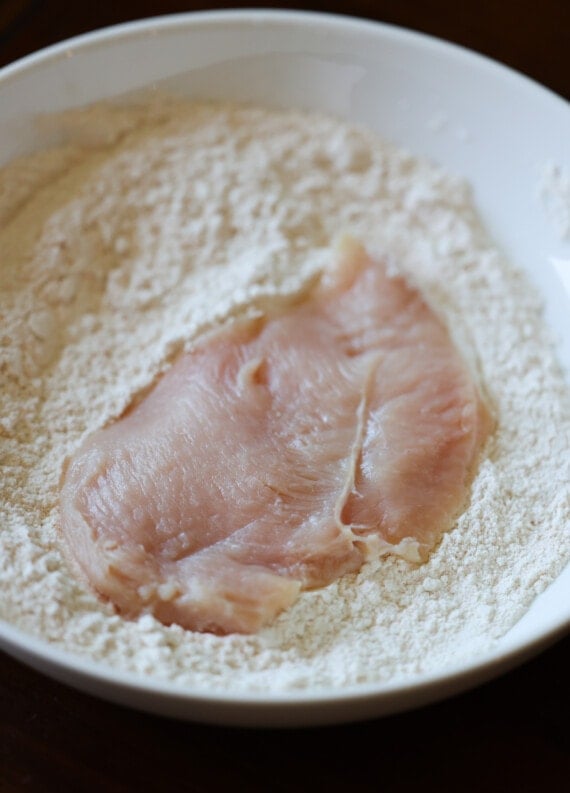 dredging a chicken cutlet in flour