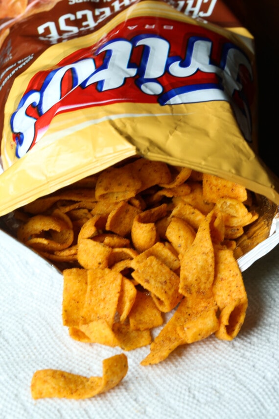An open Fritos bag with chips spilling out.