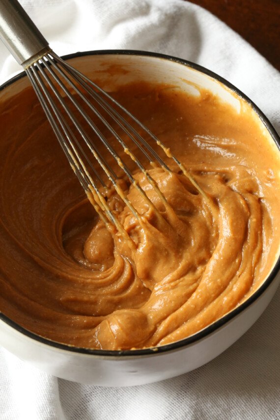 Peanut butter dressing is whisked together in a mixing bowl.