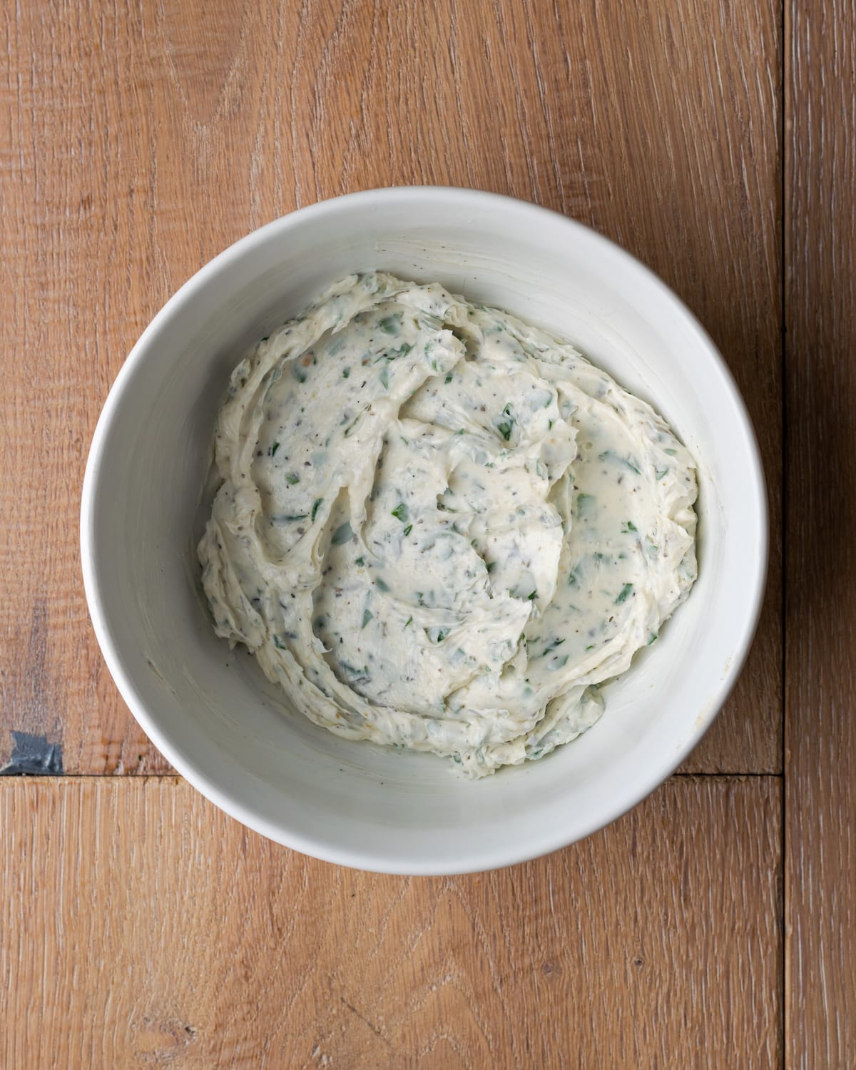 Top view of herb butter in a white bowl.