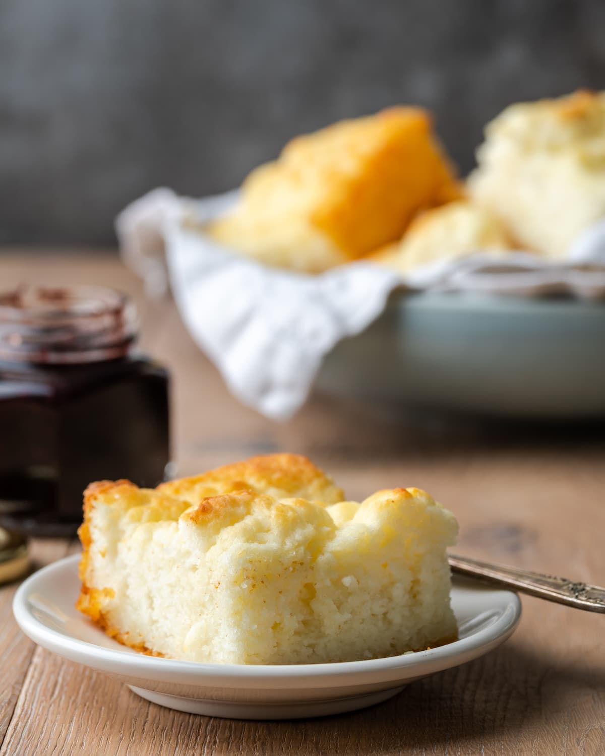 A single biscuit on a white plate, with more butter swim biscuits in a bowl in the background.