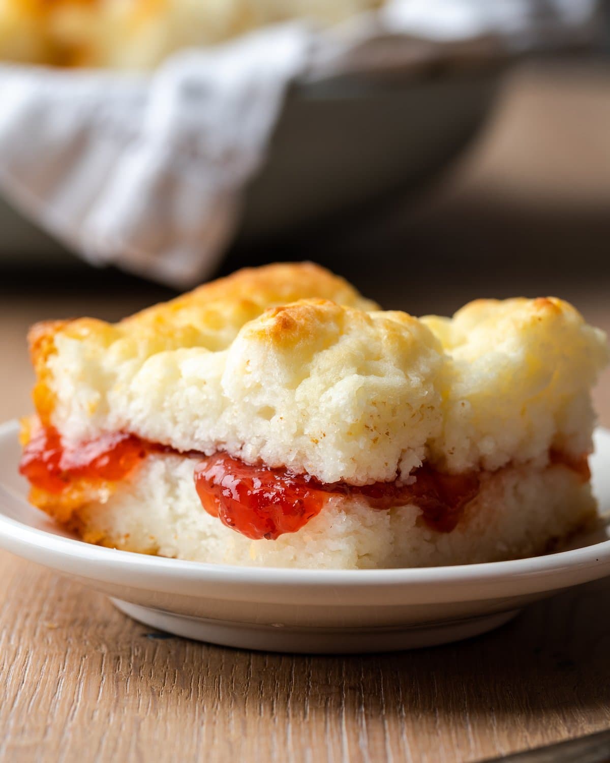 Close up of a biscuit on a plate, filled with jam.