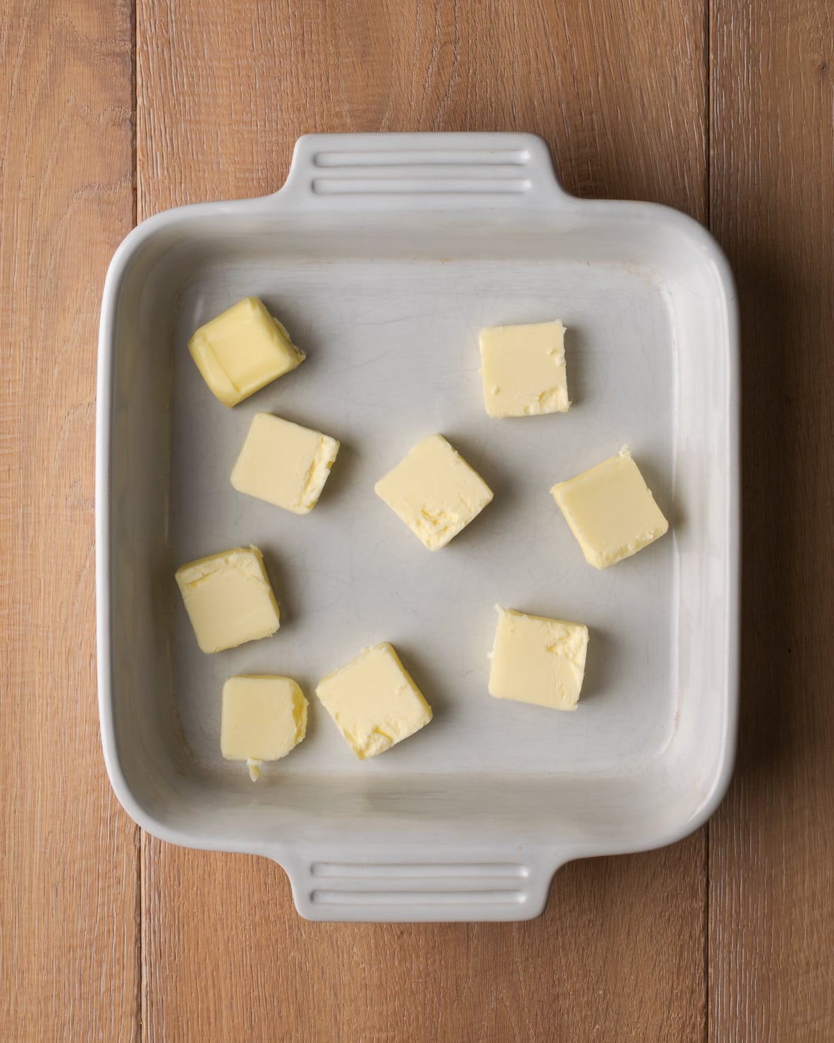 Top view of cubes of butter in a square casserole dish.