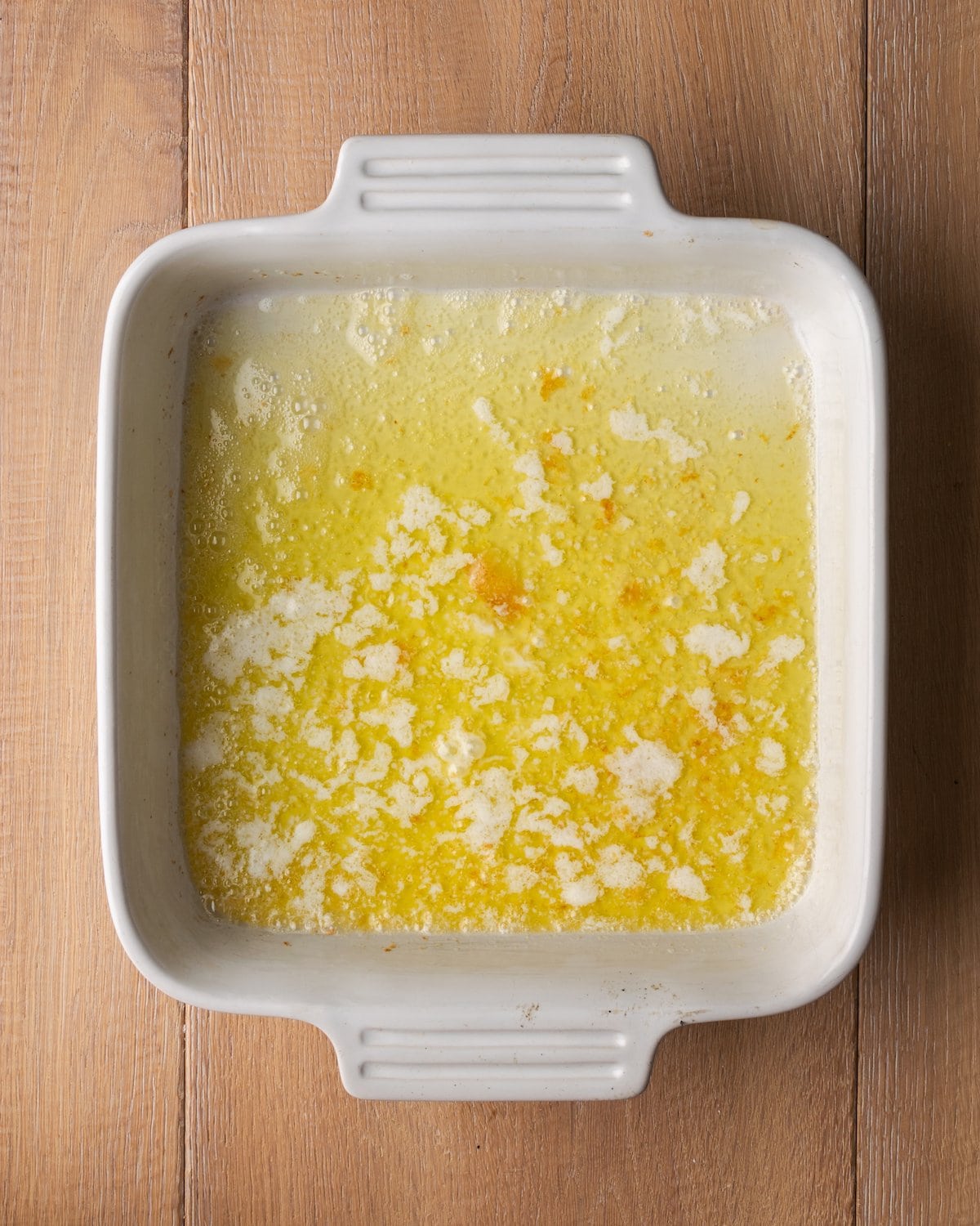 Melted butter in a square baking dish.