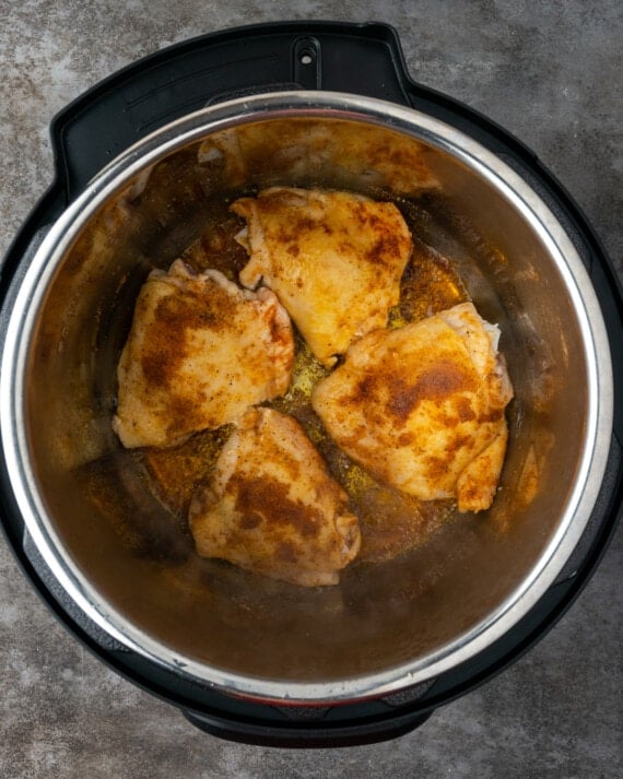 Top view of browned chicken thighs inside the instant pot.