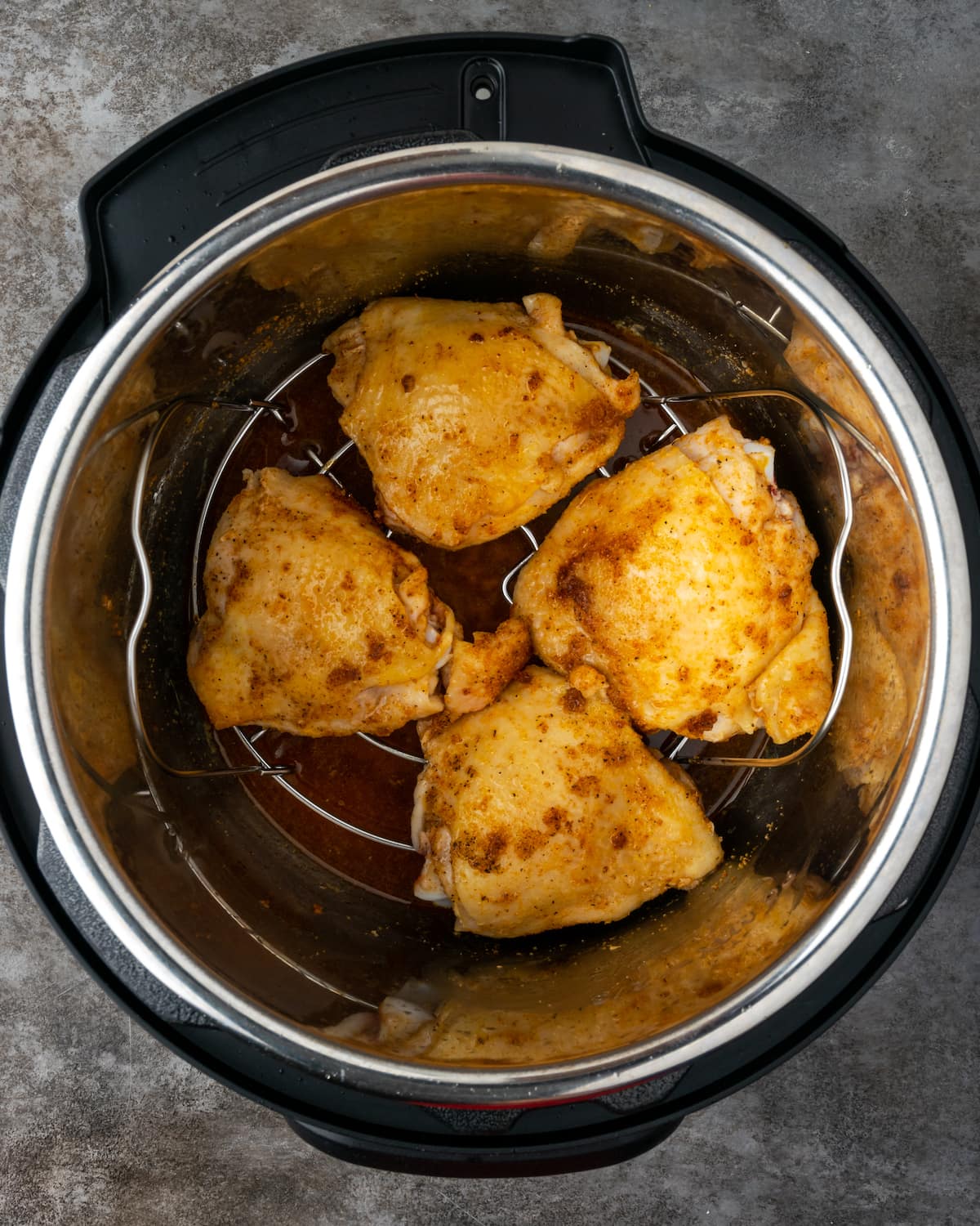 Chicken breasts on a trivet inside the instant pot, overtop of the broth.