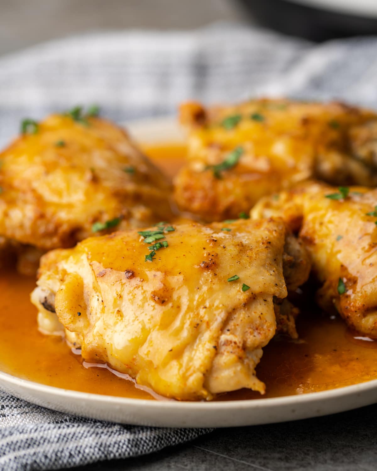 Four instant pot chicken thighs on a plate smothered with gravy.