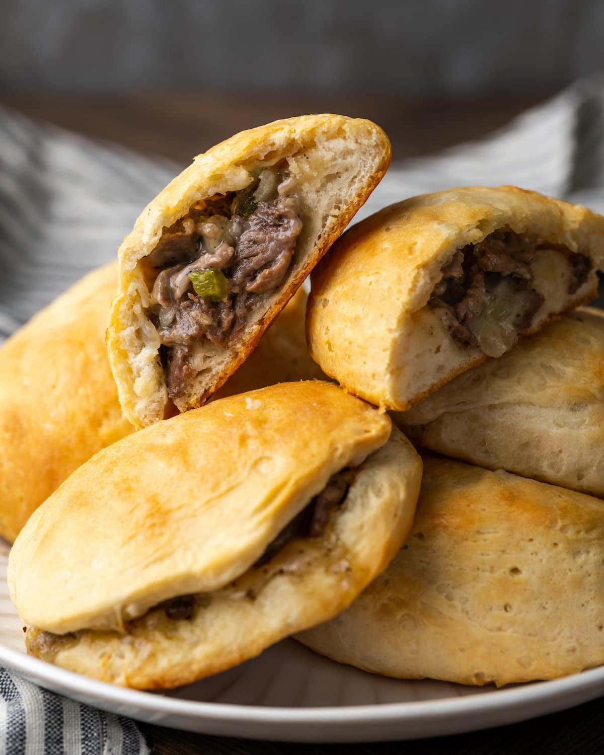 Philly cheesesteak stuffed biscuits in a pile on a plate.