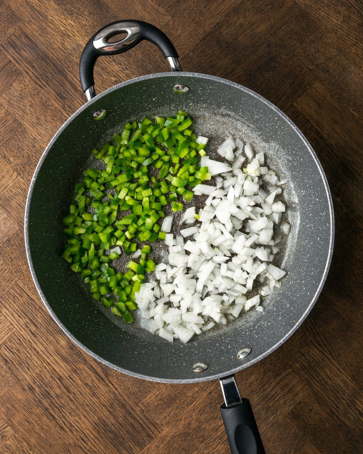 Diced onions and green bell peppers in a skillet.