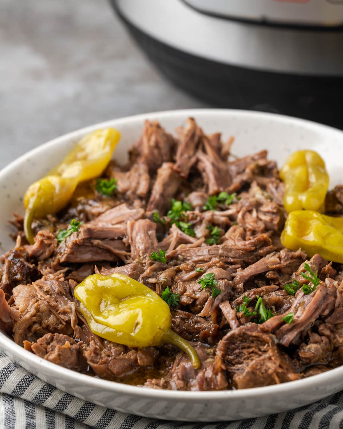 Instant Pot Mississippi pot roast on a serving platter topped with pepperoncini.