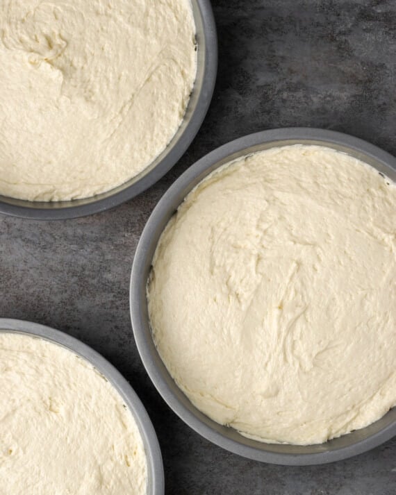 Cannoli cake batter divided between three round cake pans.