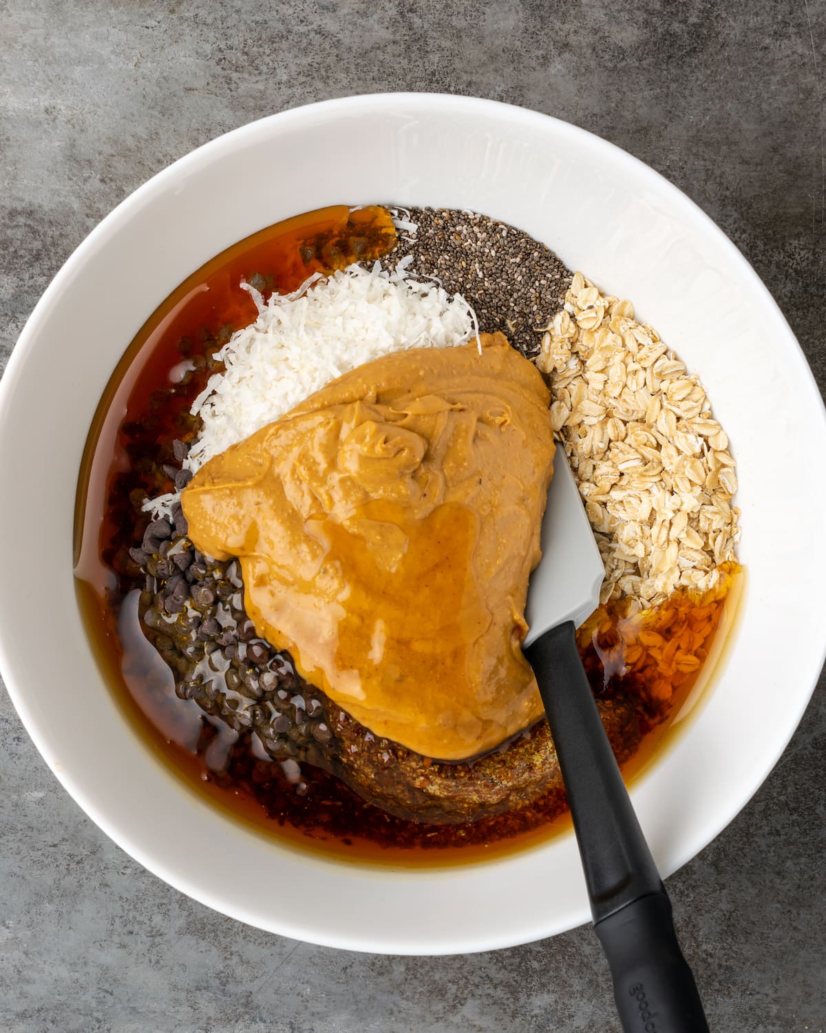 The ingredients for chocolate peanut butter energy bites combined in a white bowl.