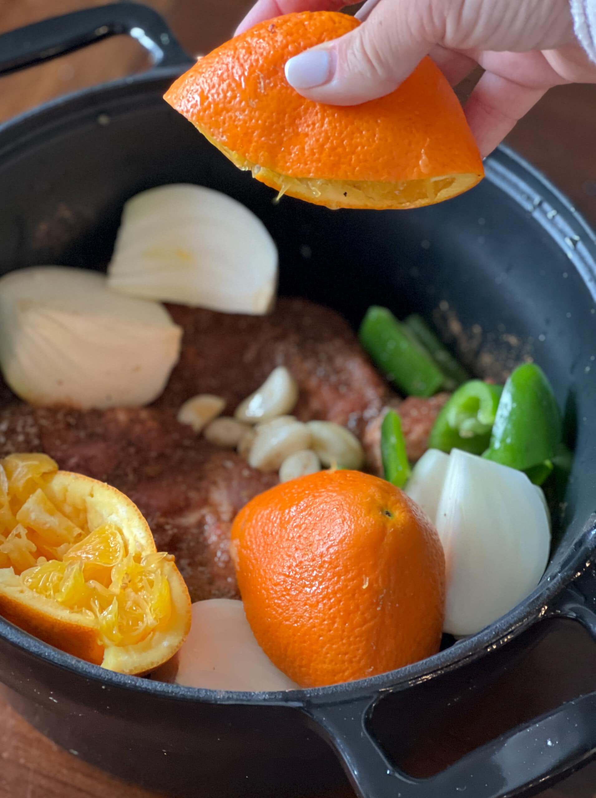 squeezing orange juice into slow cooker with pork butt