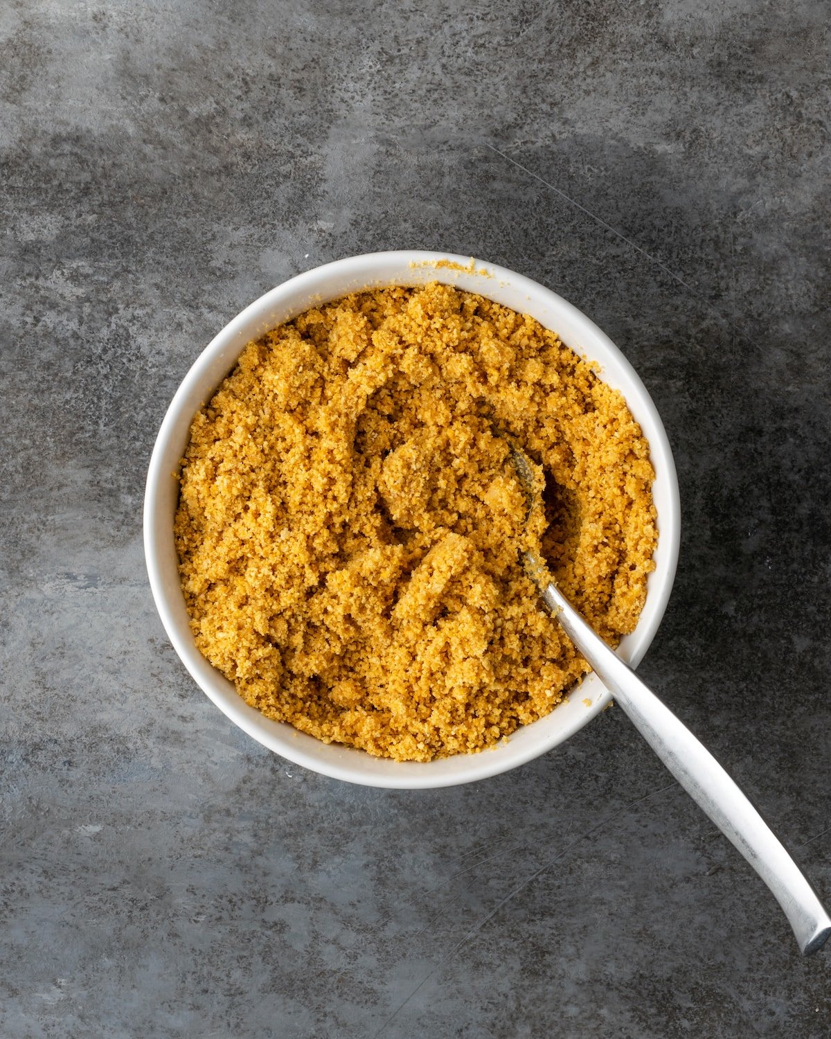 A bowl of graham cracker crumbs with a spoon.