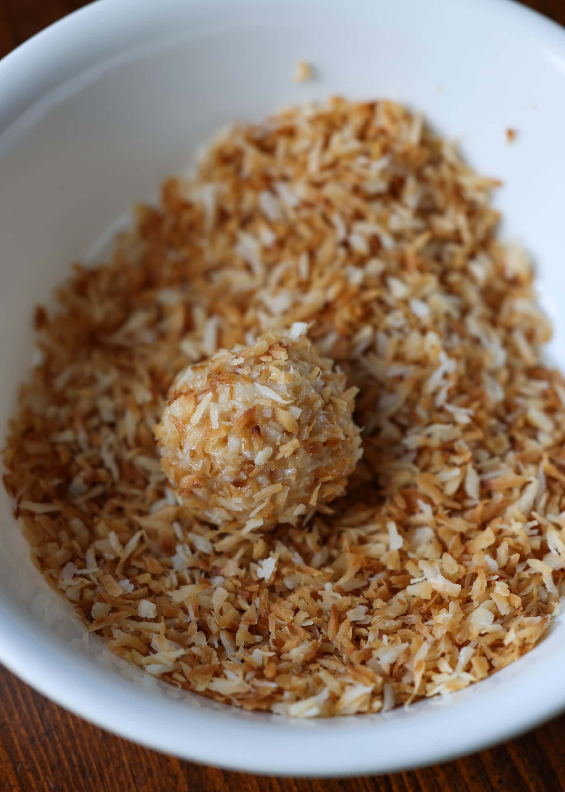 rolling coconut ball in toasted desiccated coconut