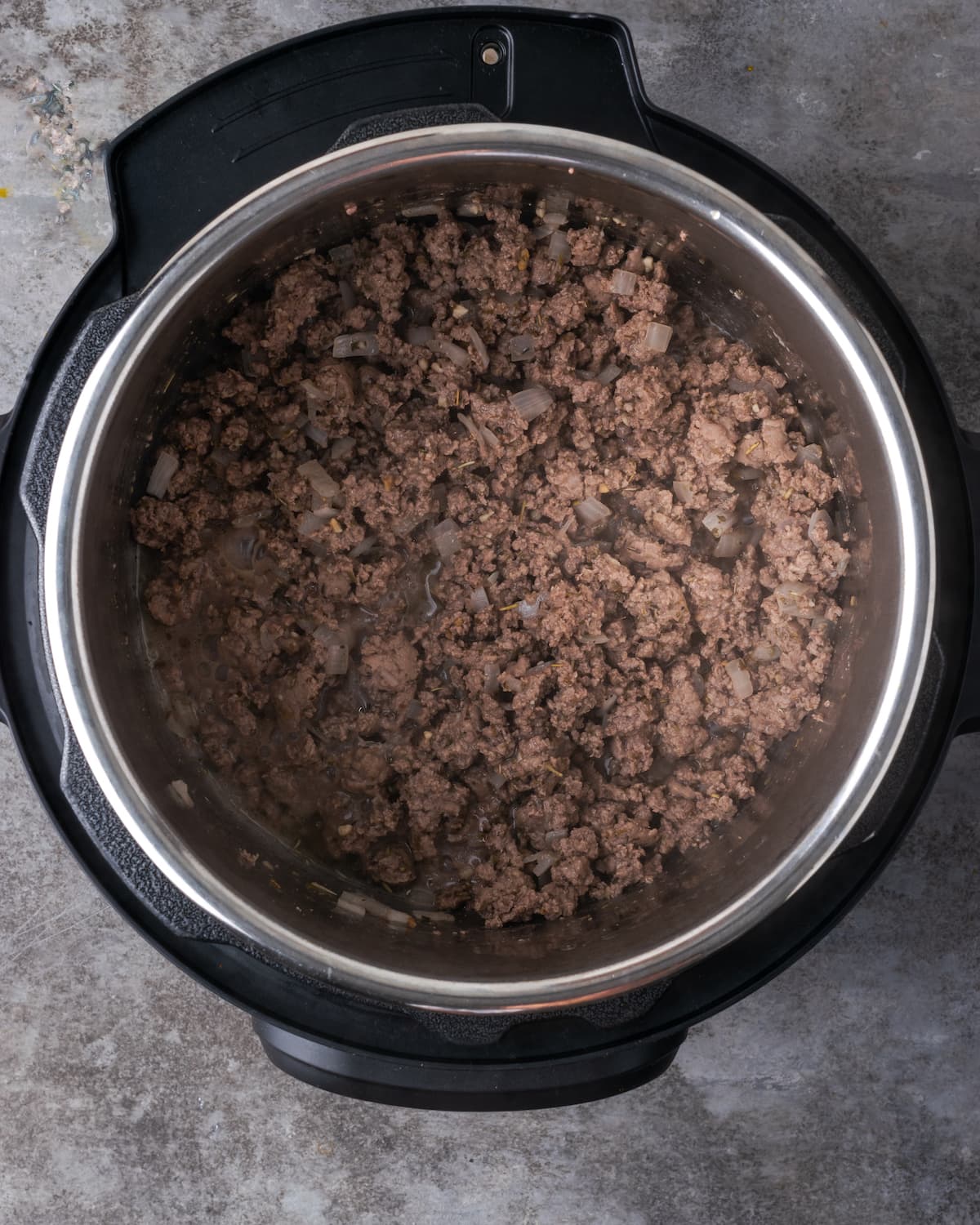 Overhead view of browned ground beef in the bottom of the instant pot.