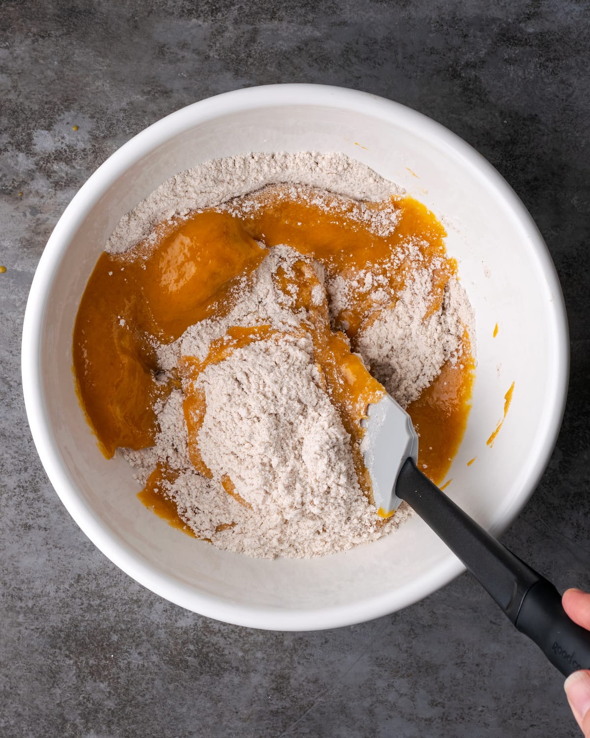 Dry ingredients added into a bowl with the wet ingredients for the pumpkin cake batter.