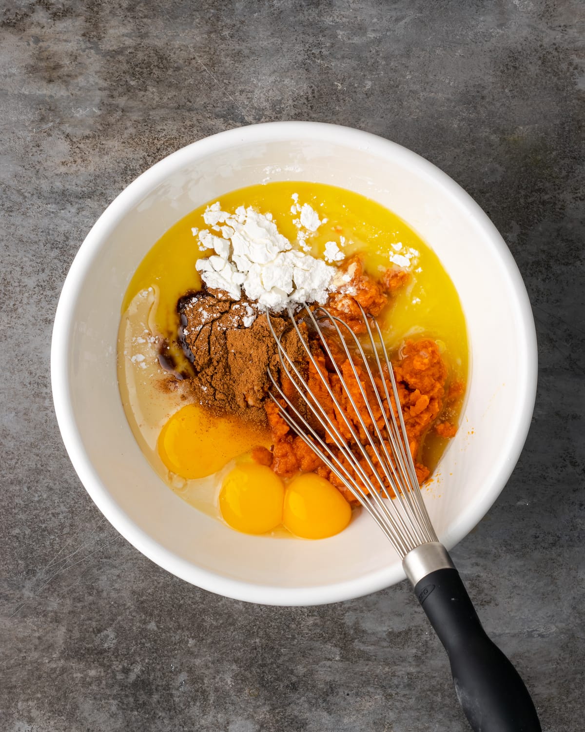 The ingredients for pumpkin pie filling combined in a mixing bowl with a whisk.