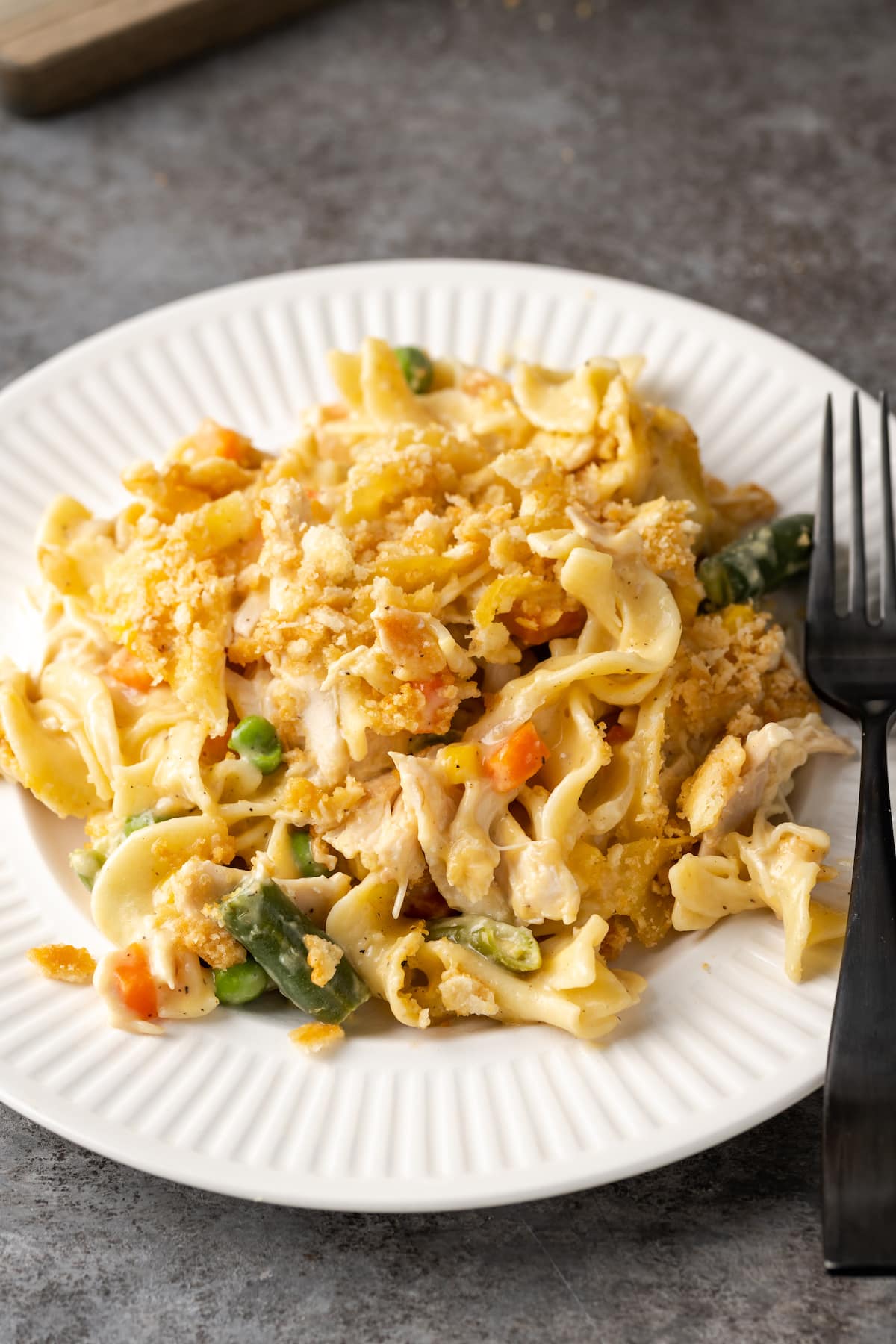 A serving of chicken noodle casserole on a white plate with a fork.