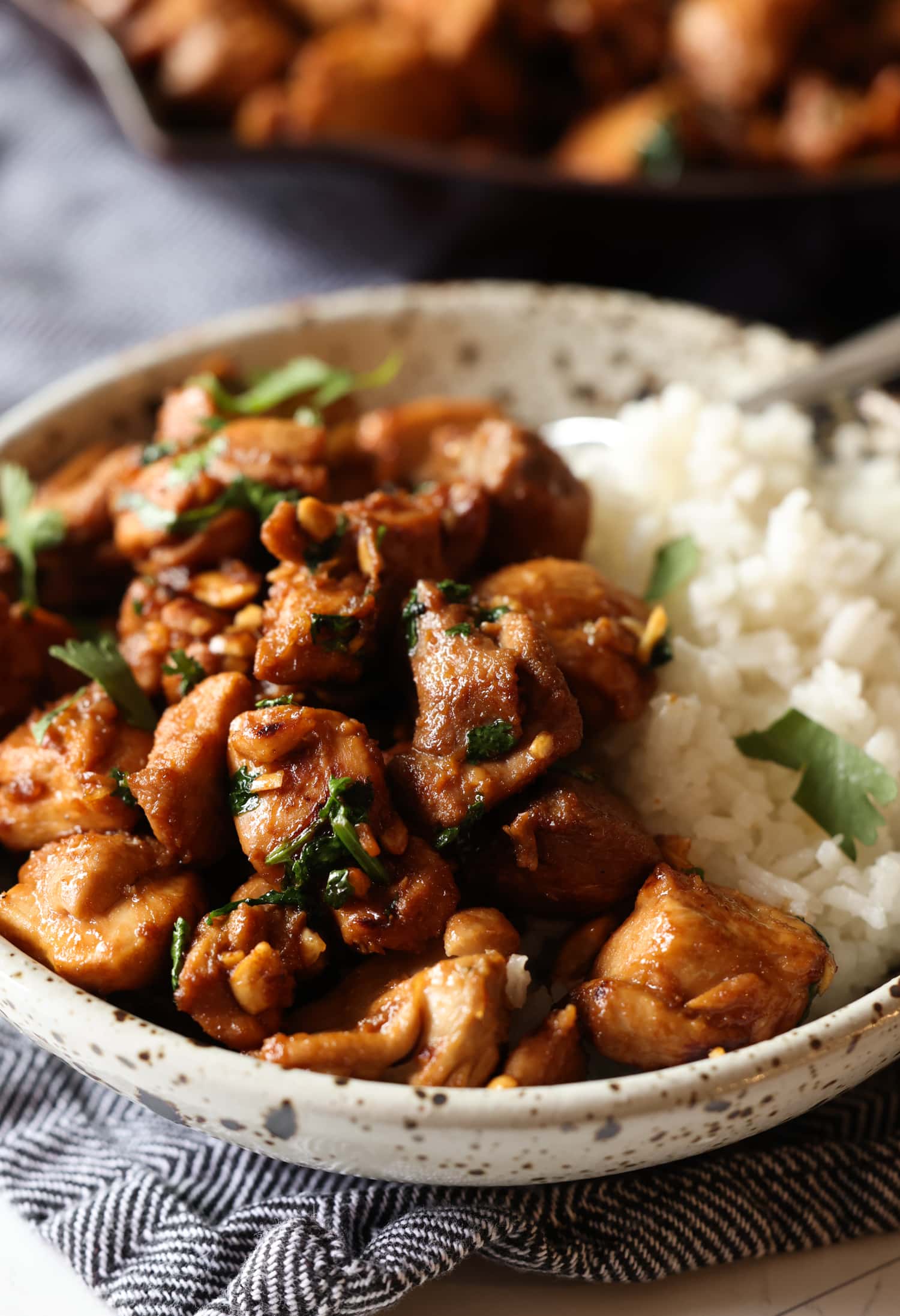 A bowl of ginger chicken is served over rice and garnished with chopped fresh coriander.