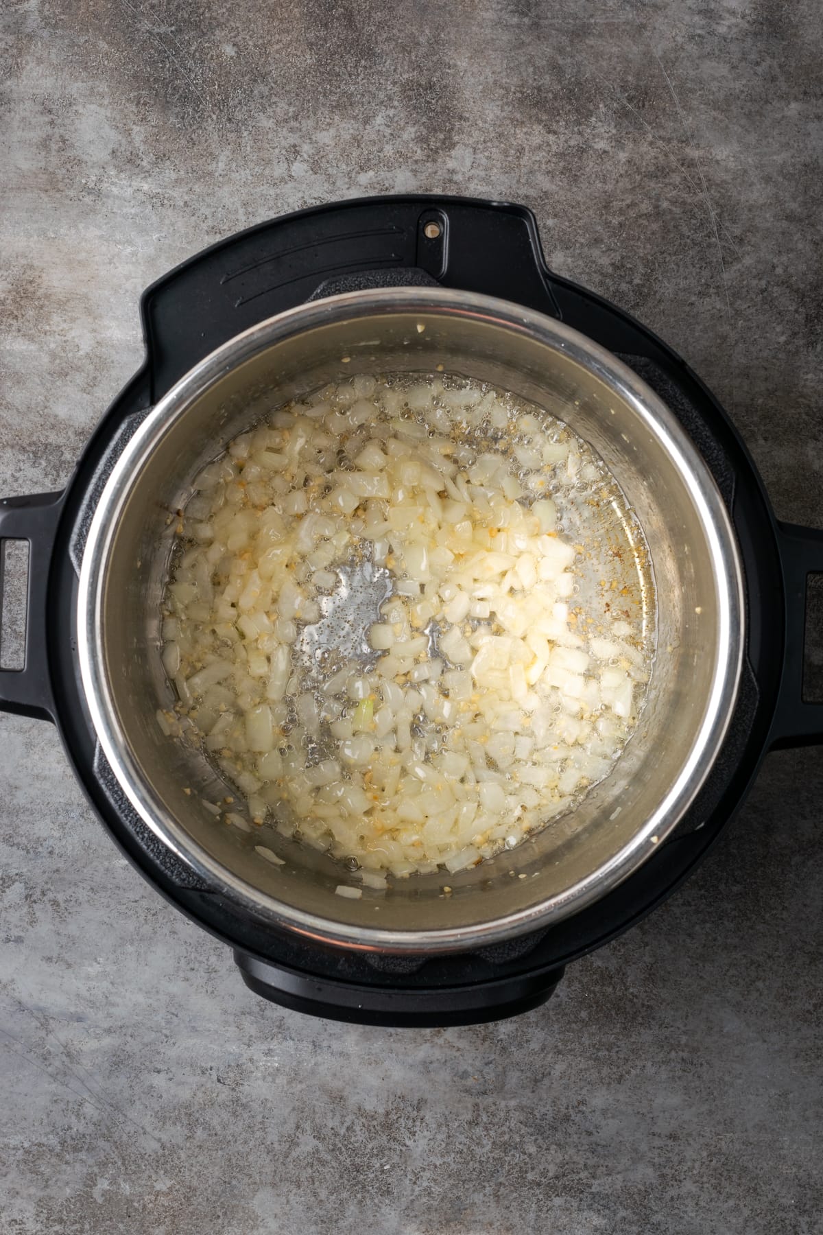 Diced onions and garlic sautéing inside an Instant Pot.