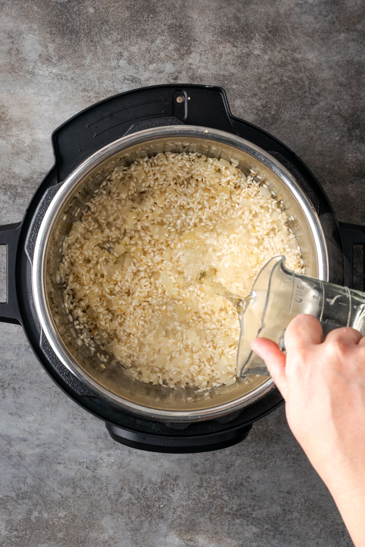 White wine is poured over arborio rice inside an Instant Pot.