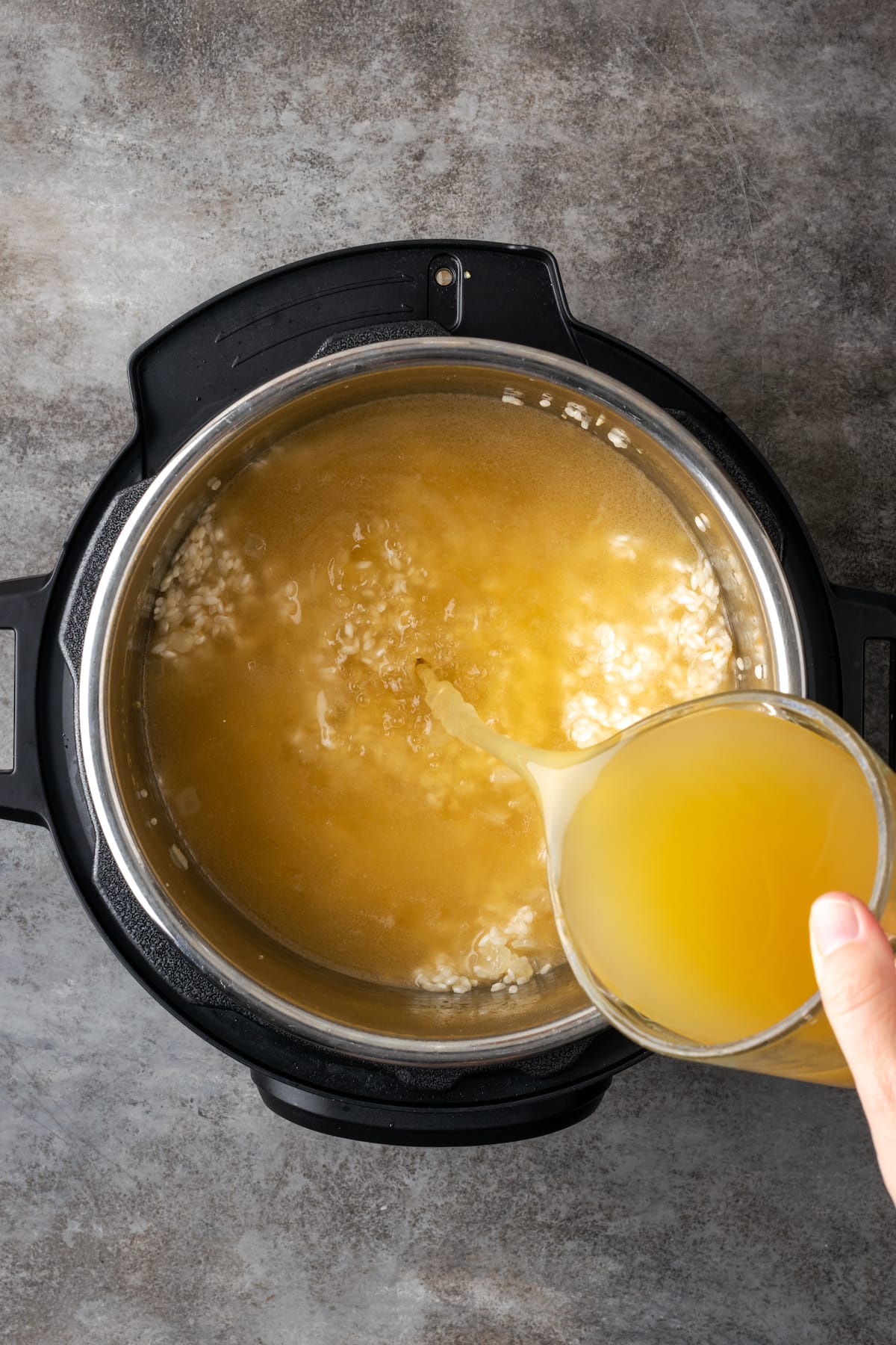 Chicken broth is added to rice in the Instant Pot.