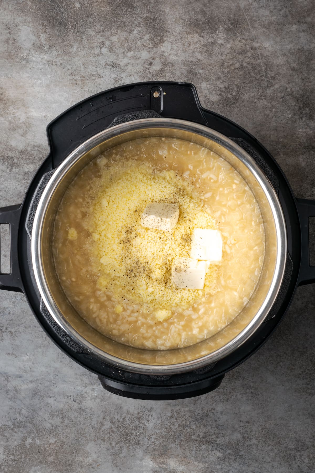 Butter and parmesan cheese is added to risotto inside an Instant Pot.