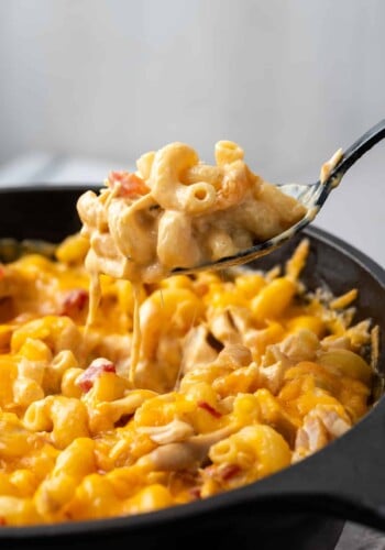 A spoon scooping mac and cheese in a skillet