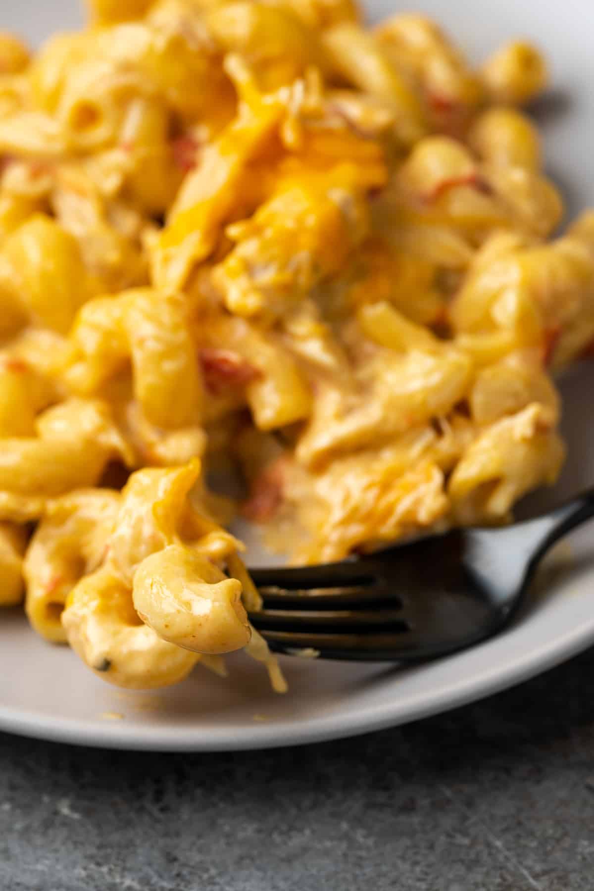 A serving of mac and cheese on a plate with a fork