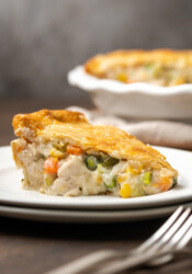 A slice of chicken pot pie on a white plate next to a fork.