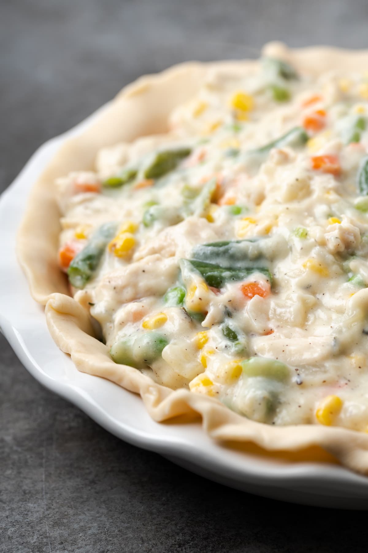 Chicken pot pie filling in a flaky crust inside a pie plate.