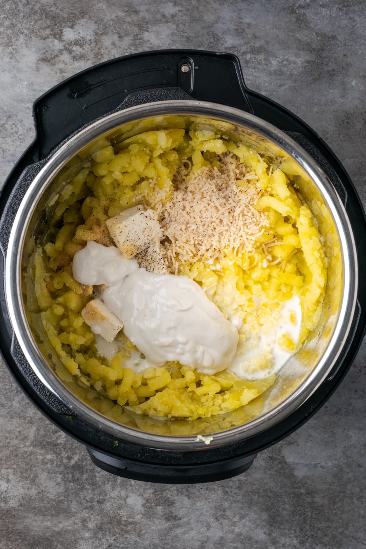 Seasonings, sour cream, and butter added to mashed potatoes inside the Instant Pot.