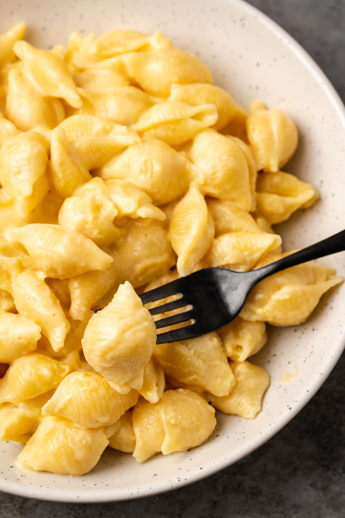 Dieser Mac and Cheese auf dem Herd ist ein klassisches Hausmannskost, das in einem Topf mit nur 5 Zutaten zubereitet wird! Selbstgemachter Mac and Cheese war noch nie so einfach. Eine Gabel, die einen Bissen von einer Schüssel Makkaroni und Käse aufnimmt.