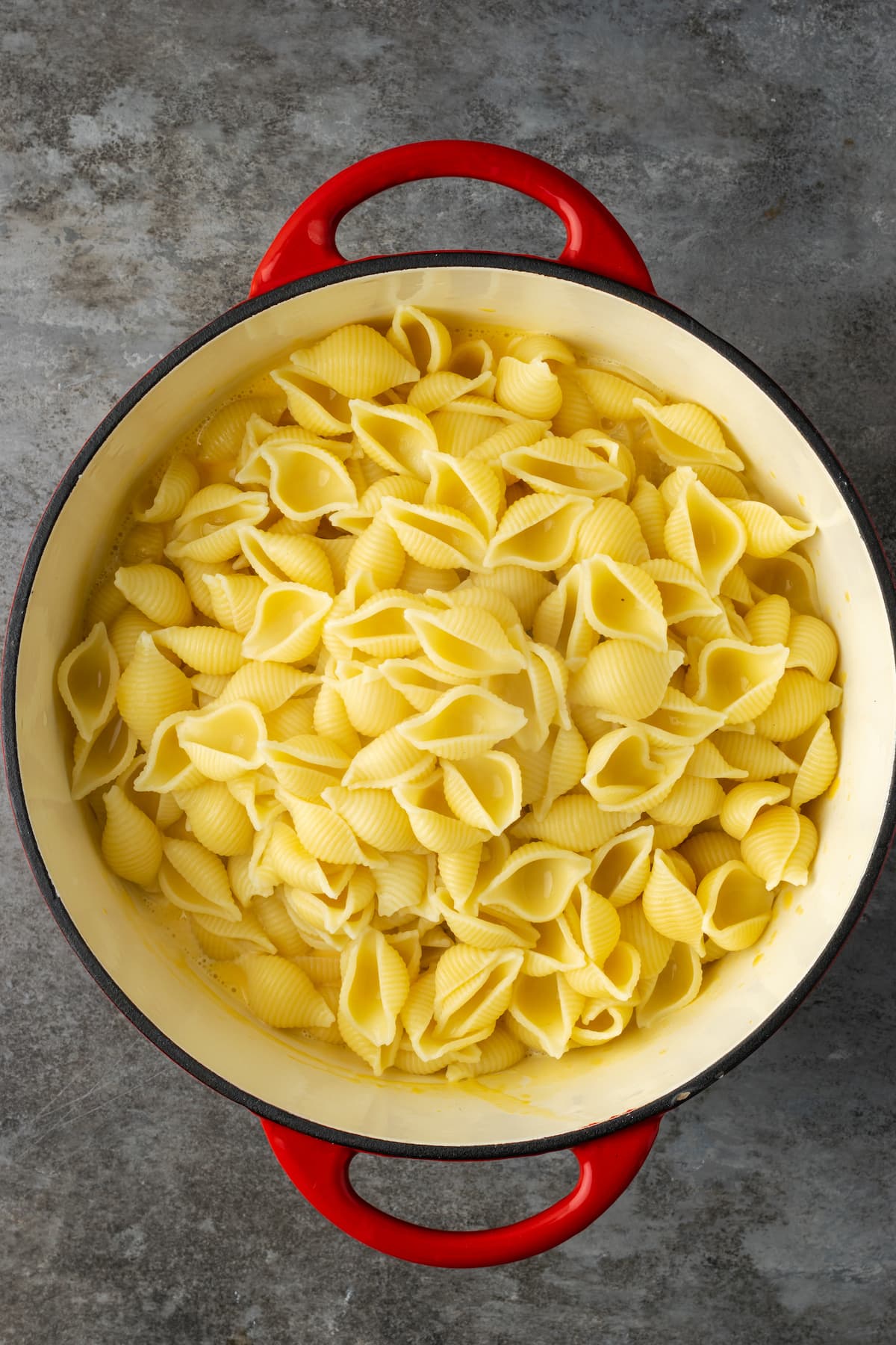 Cooked shell pasta added to a large pot.