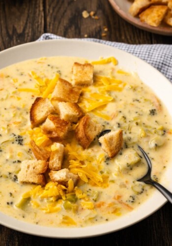 A bowl of instant pot broccoli cheddar soup topped with croutons with a spoon.