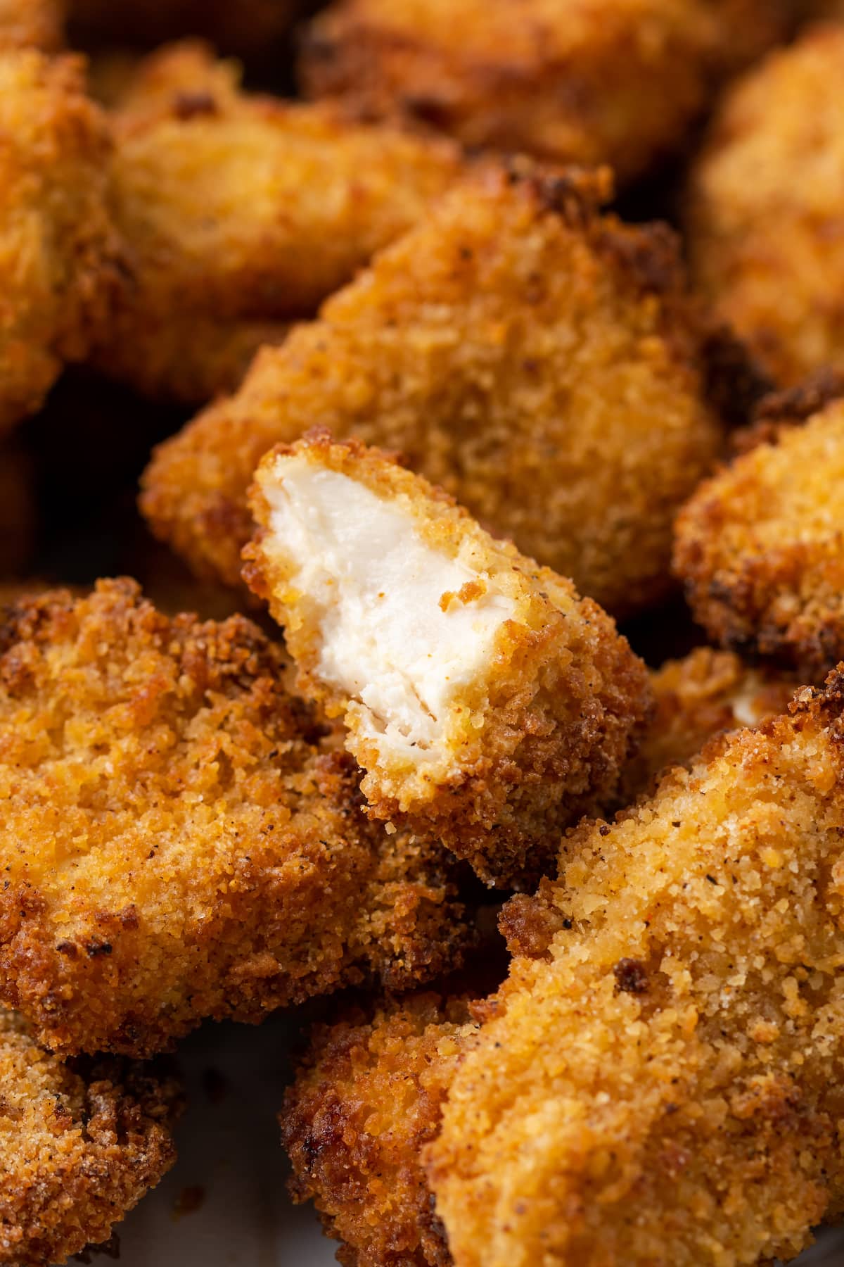 Close up of air fryer popcorn chicken with a bite missing from a nugget.