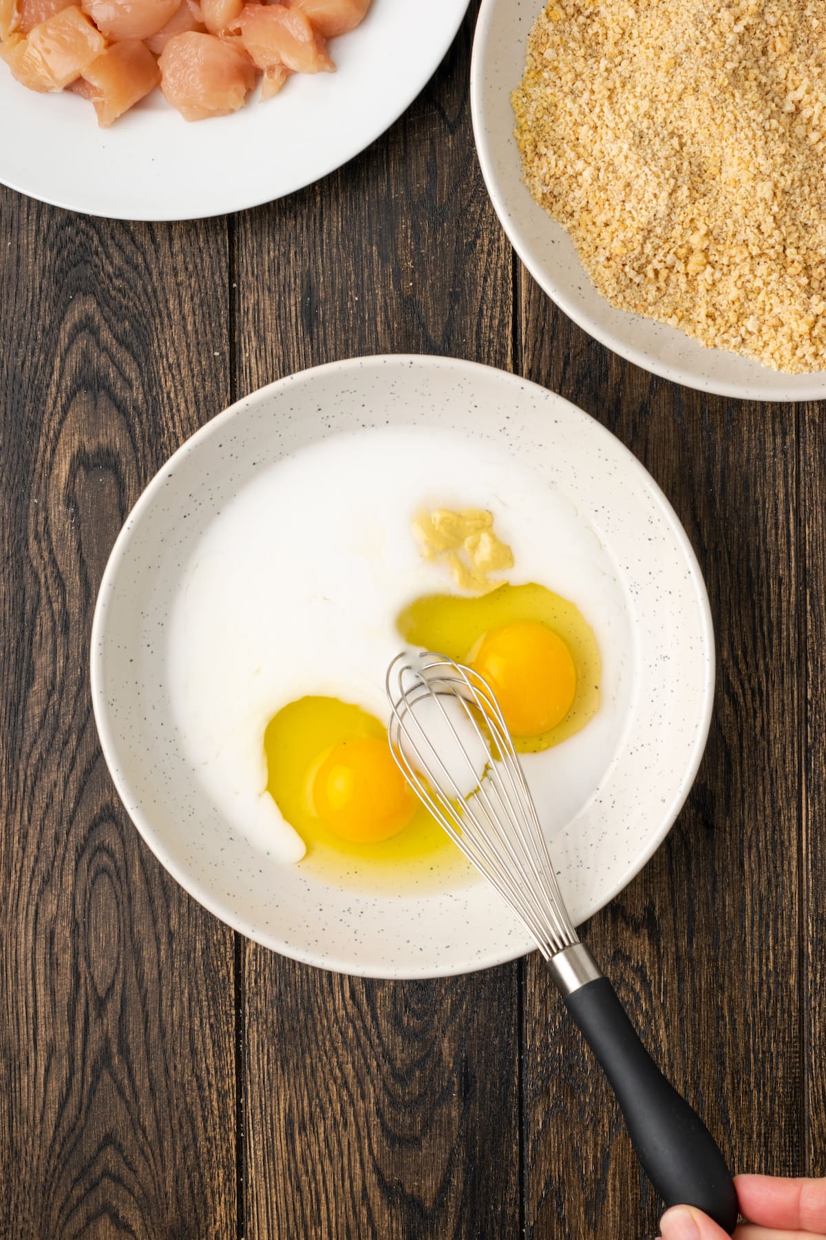 Eggs and milk are whisked together in a white bowl for an egg wash.