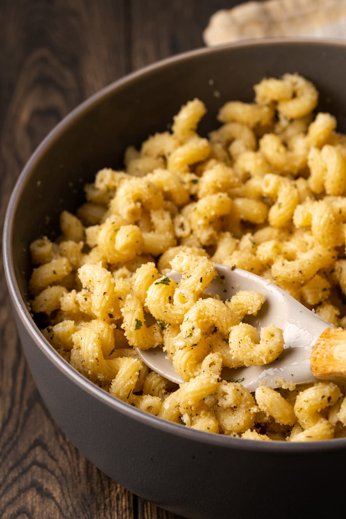 Close up of garlic bread pasta in a pot with a serving spoon.