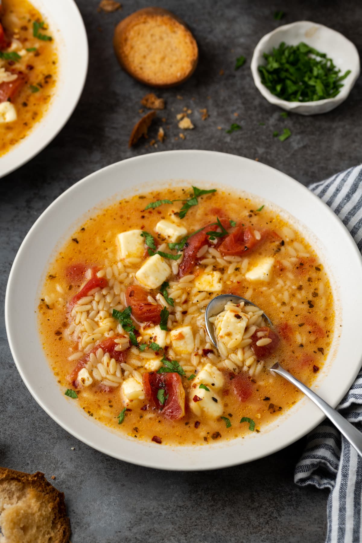 Overhead view of a bowl of Greek tomato feta soup with a spoon.