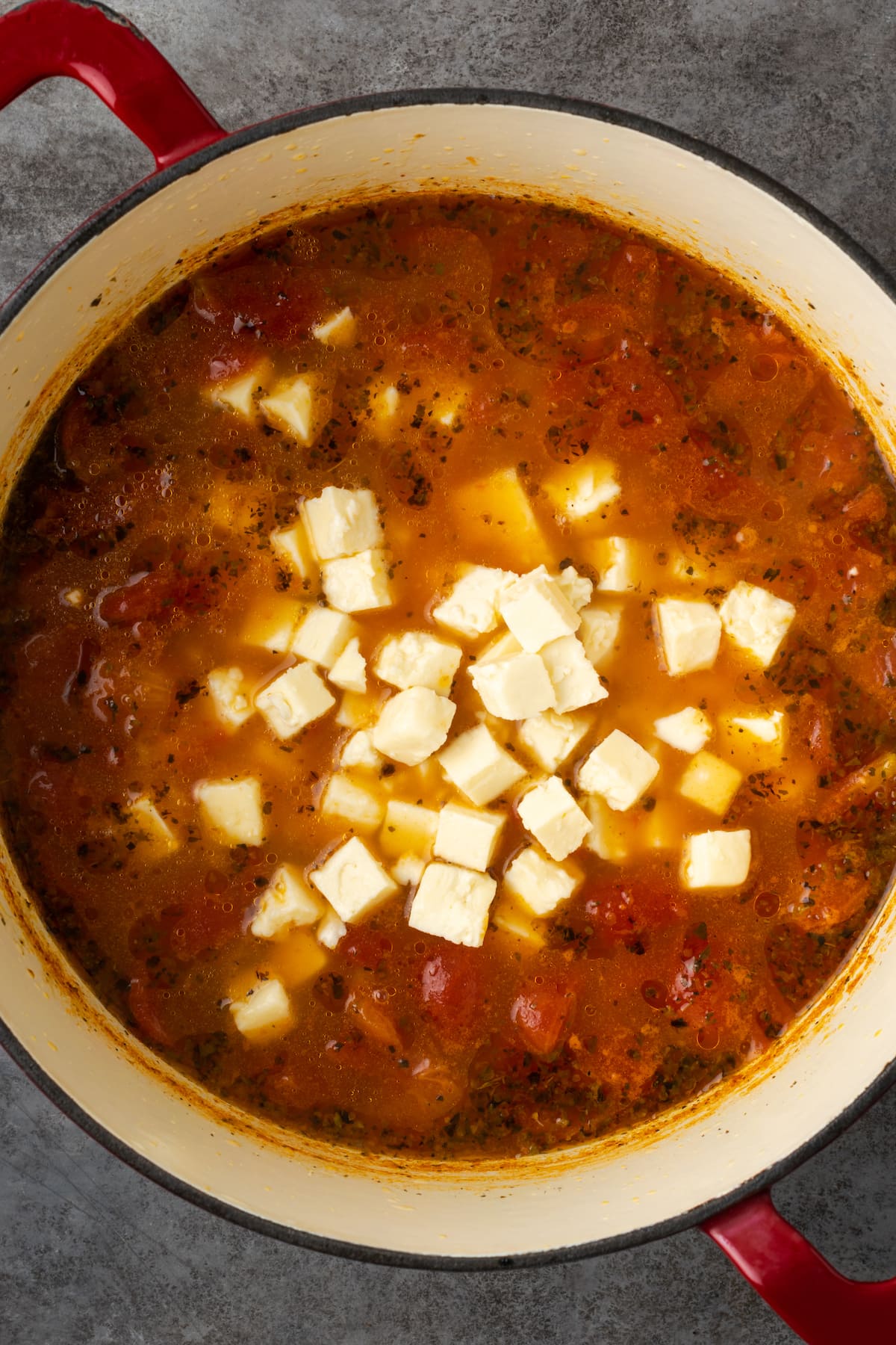 Feta cheese added to a pot of tomato soup.