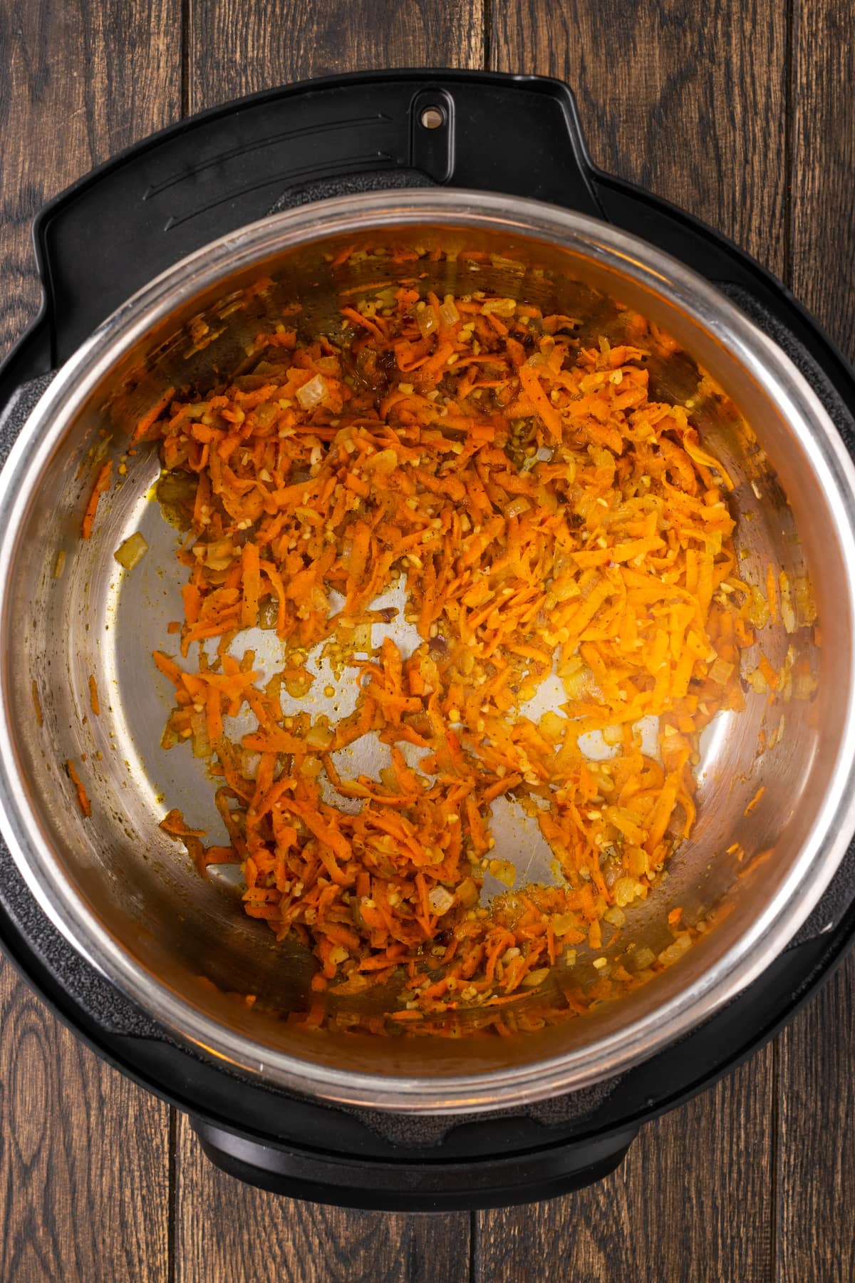 Sauteed carrots and onions in the bottom of an instant pot.