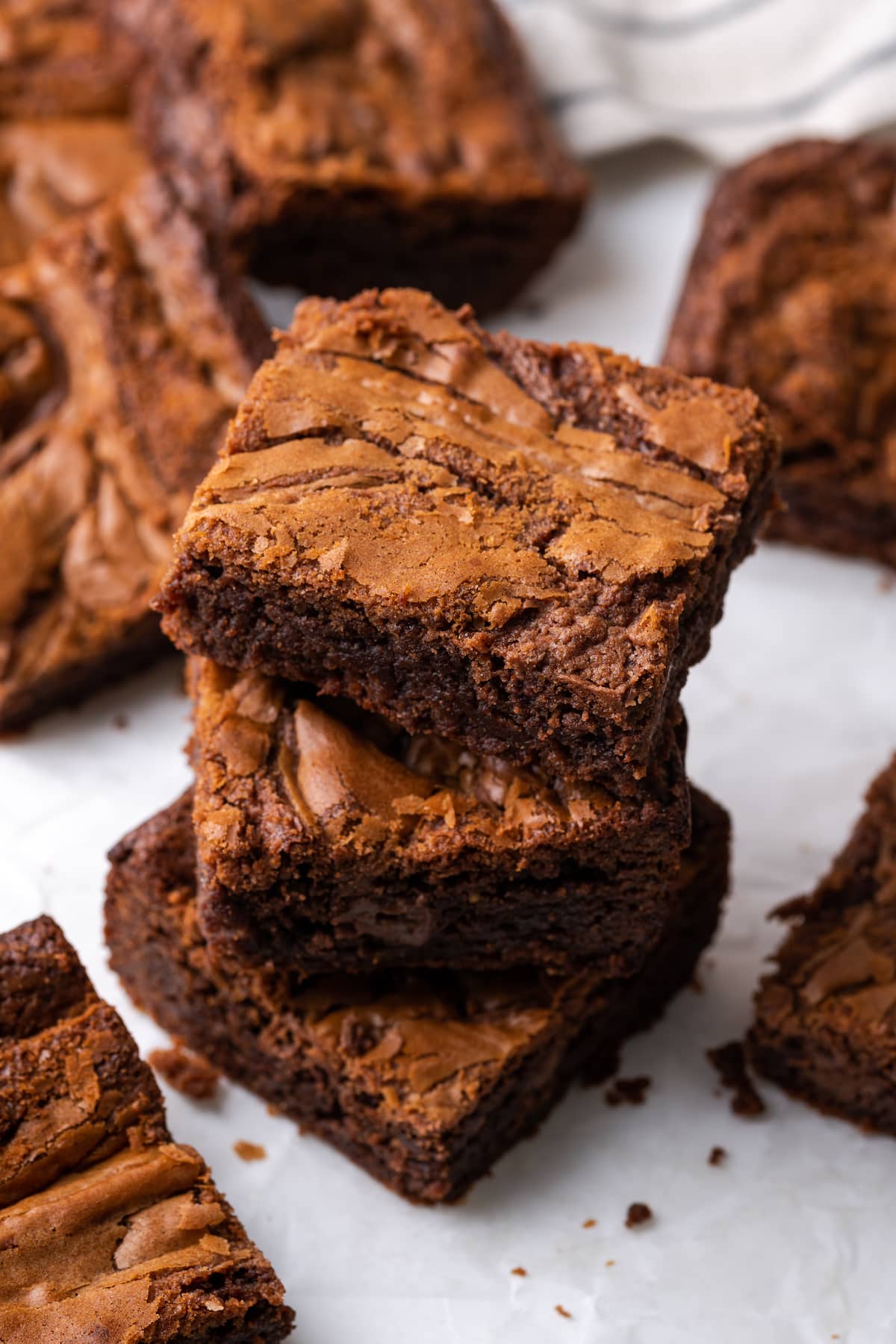 An overhead view of three Nutella brownies stacked on a cutting board and surrounded by more brownies.