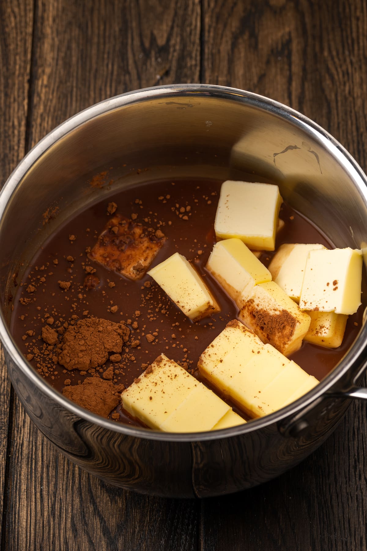 Cubes of butter and cocoa powder combined in a saucepan.